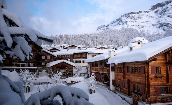 Snow-covered chalet surrounded by mountains under a clear winter sky