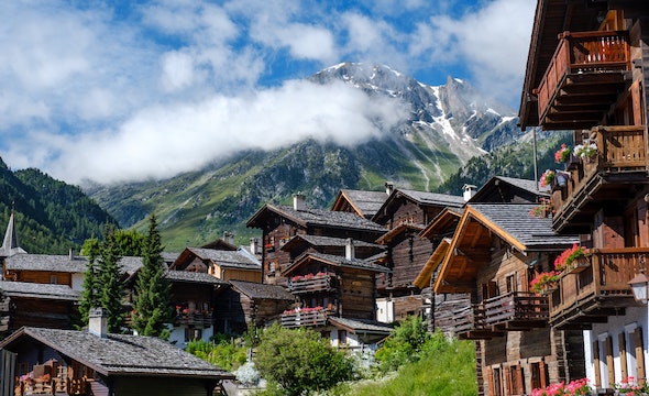 Traditional Swiss chalet with wooden balconies and snowy peaks in the background